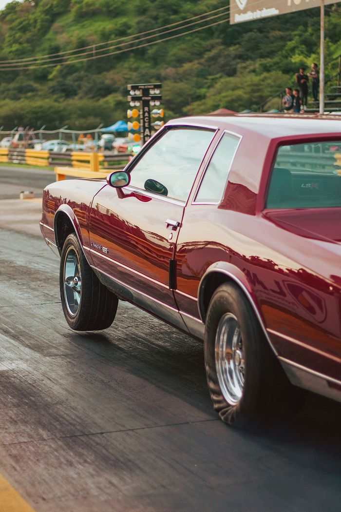 contact-img Vintage red car participating in a drag race on an asphalt track in Turagua, Venezuela.
